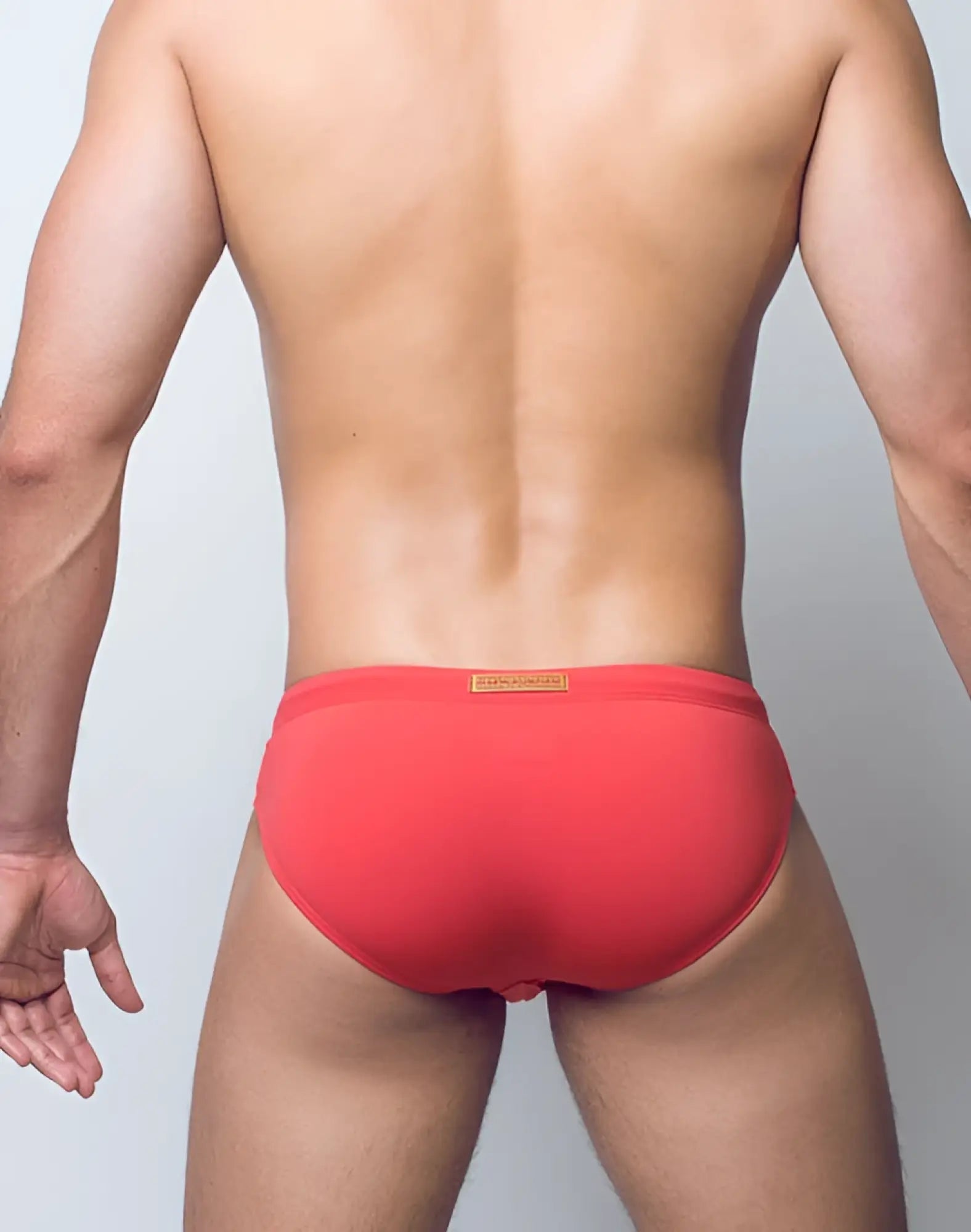 Red 2eros v10 core series 2 swimwear briefs with a coral hue and a small orange label at the waistband