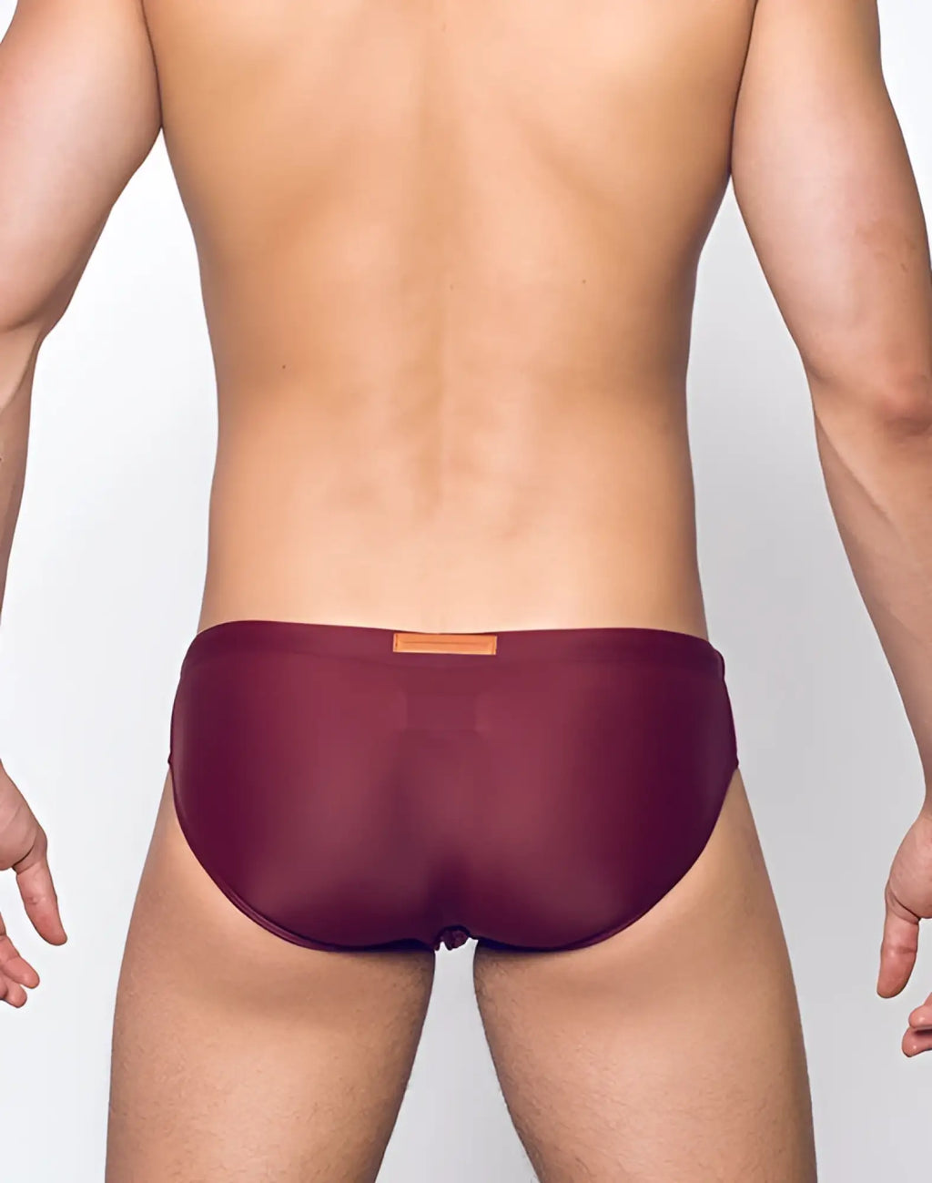 Maroon sheer 2EROS V10 Core swim trunks with a small orange label at the waistband in tawny port color