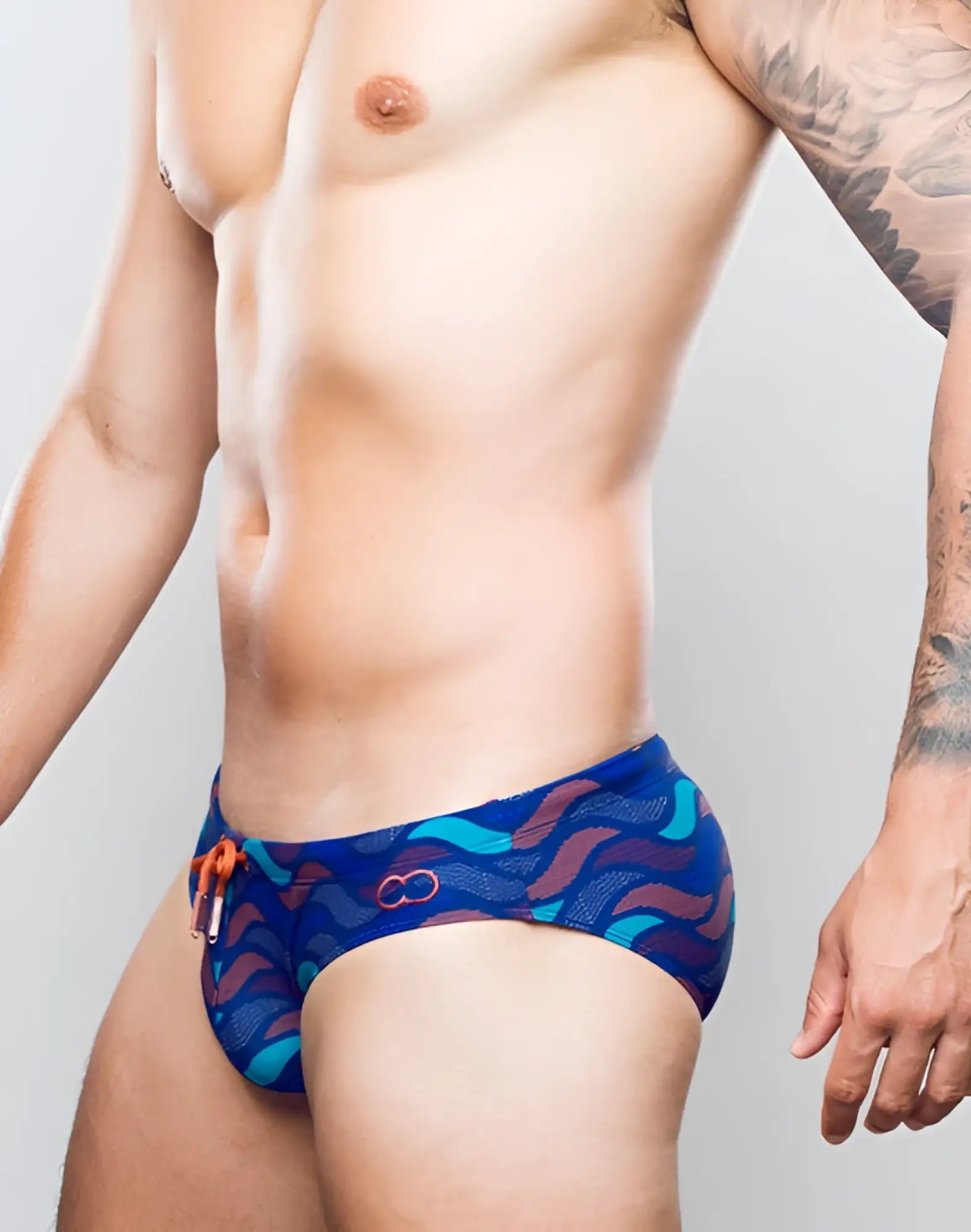 Blue swim trunks 2EROS V10 print with teal and maroon wavy pattern orange drawstring and circular logo on front