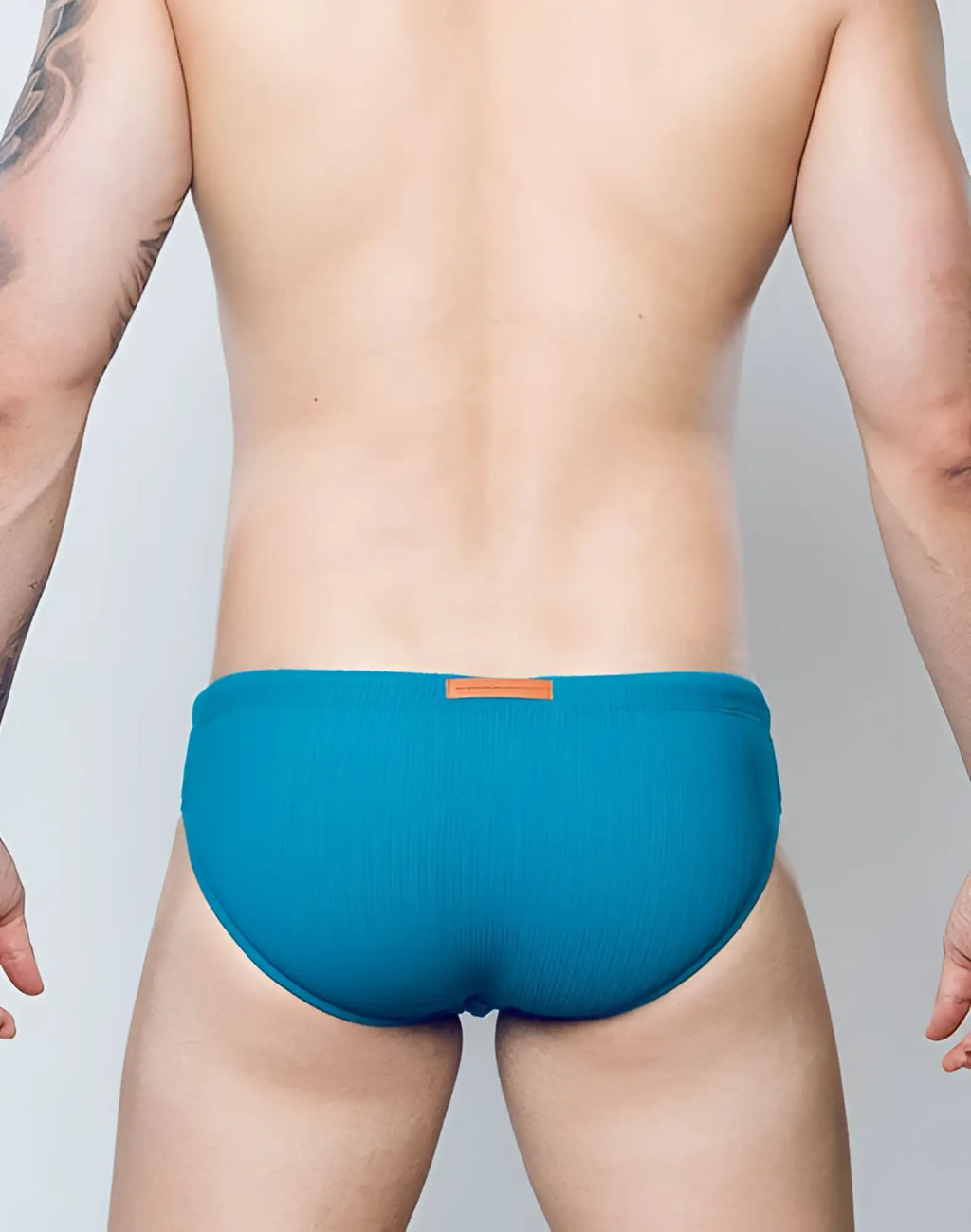 2EROS V10 swim brief in railroad teal with ribbed texture and small orange tag at the waistband