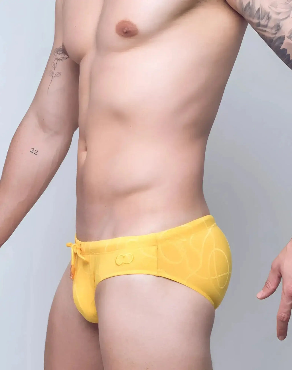 Bright yellow 2EROS V10 textured swim brief with subtle abstract pattern and orange drawstring for swimwear use