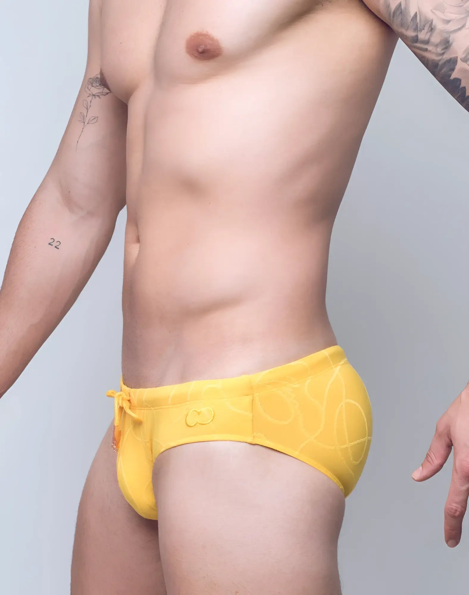 Bright yellow 2EROS V10 textured swim brief with subtle abstract pattern and orange drawstring for swimwear use