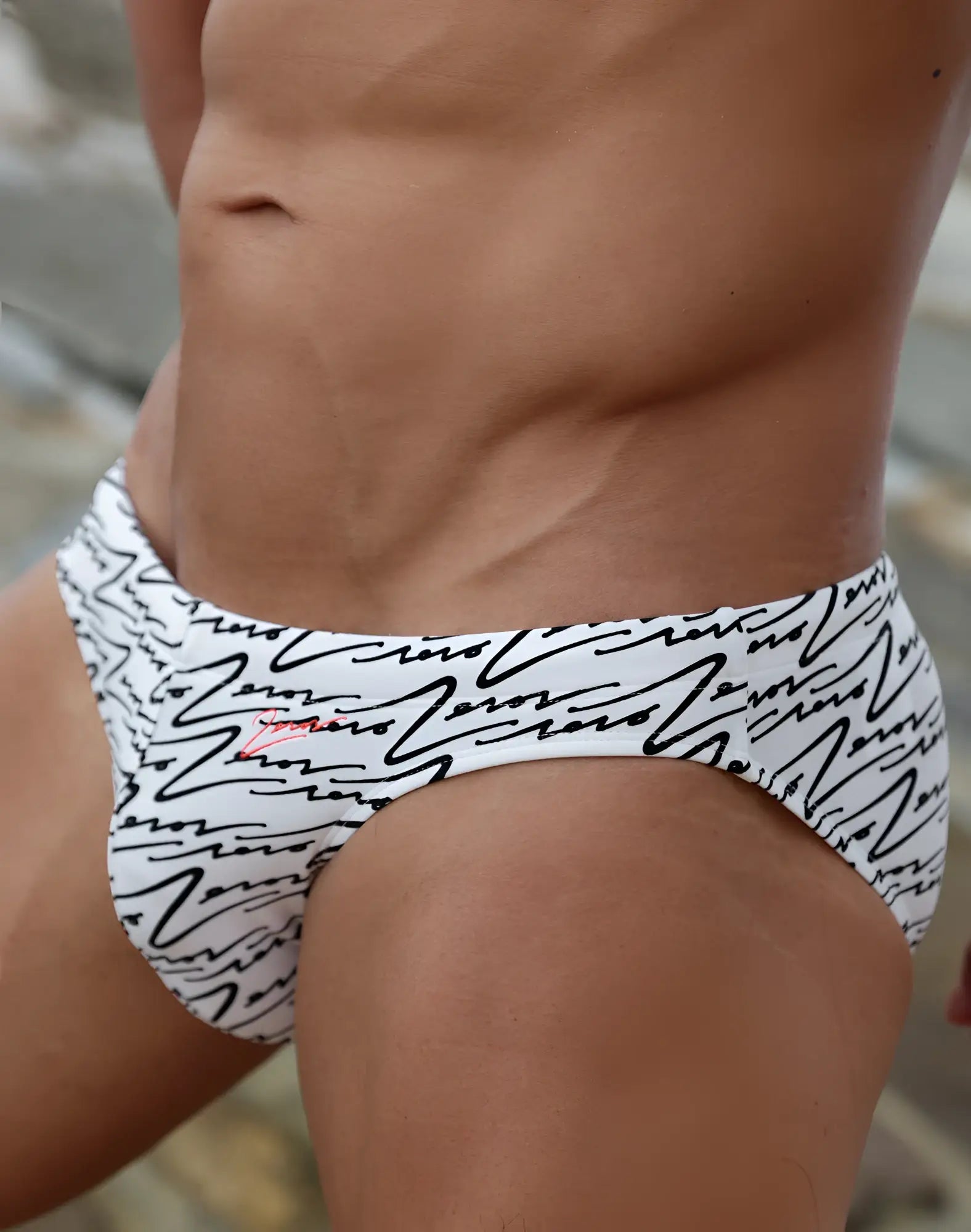 White swim briefs by 2EROS with black abstract line patterns and a small red logo on the left hip