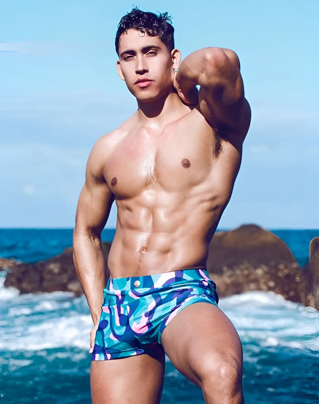 The man is wearing 2EROS V60 Bondi print swim trunks in kai blue with a bold blue and purple abstract design