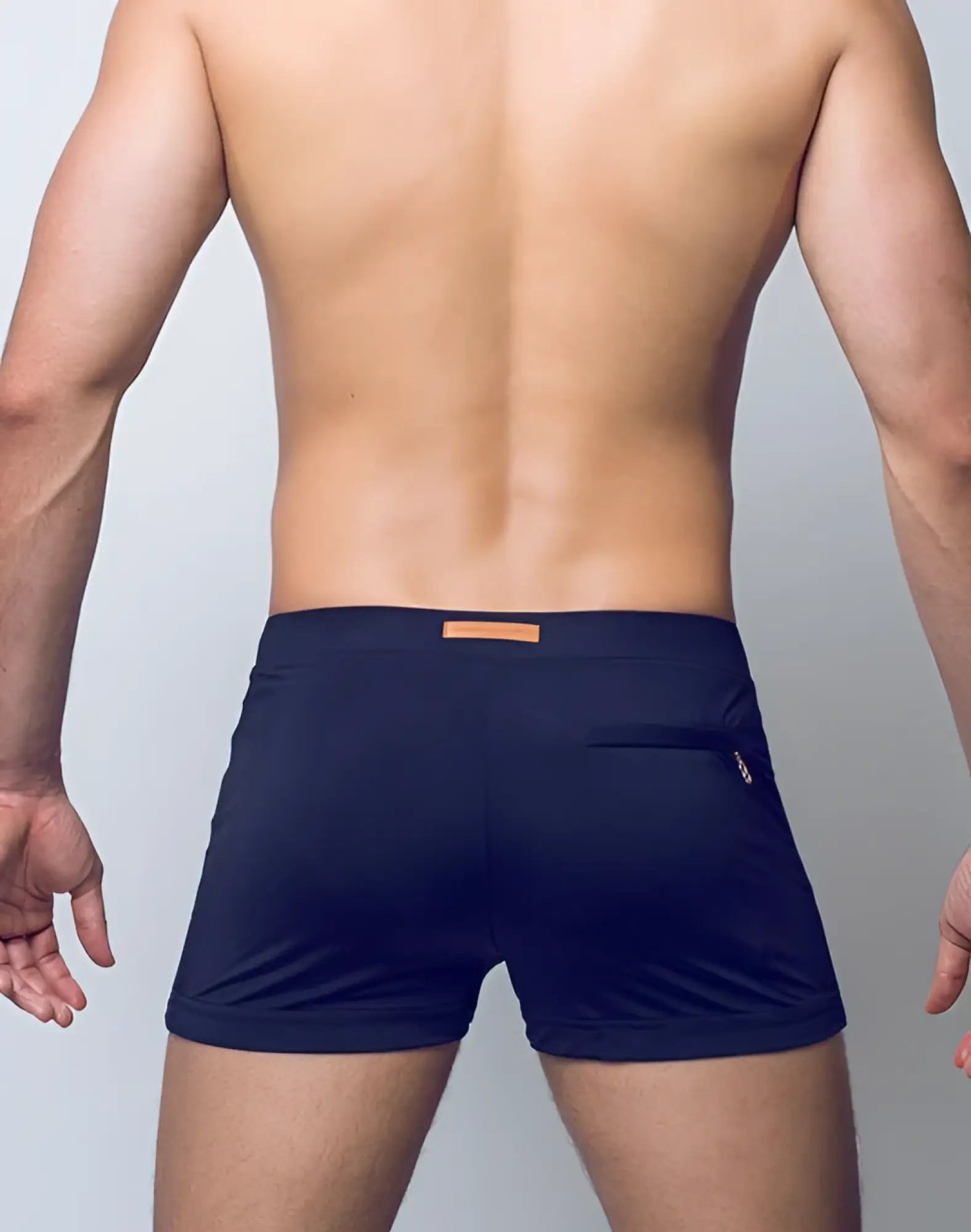 Back view of navy blue 2EROS V60 Bondi Series 2 swim trunks with tan leather patch and zippered pocket on the waistband