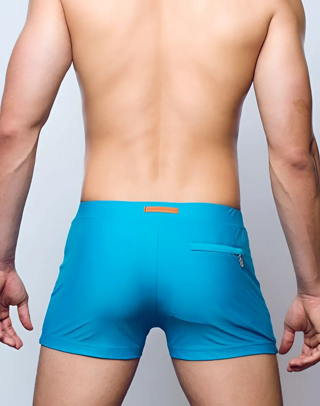 Back view of 2eros v60 bondi breeze green swim trunks with bright turquoise fabric orange tag and zippered pocket