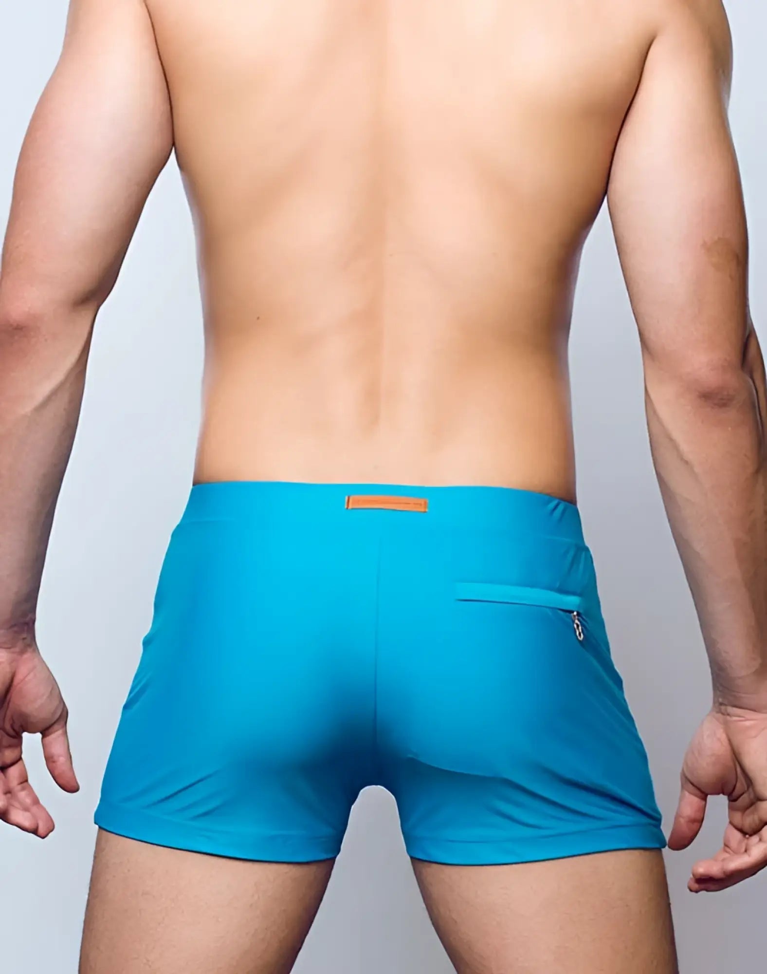 Back view of 2eros v60 bondi breeze green swim trunks with bright turquoise fabric orange tag and zippered pocket