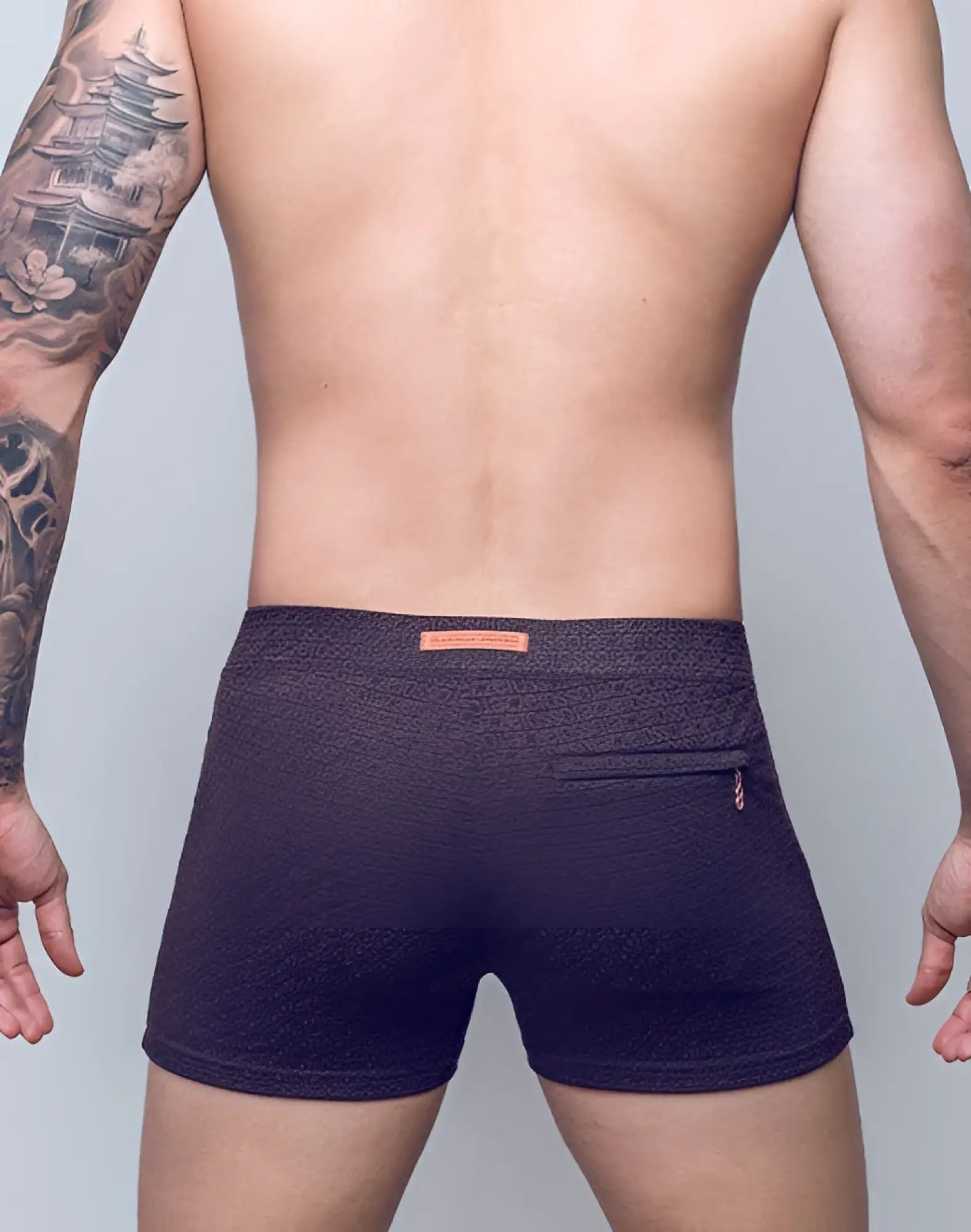 Dark purple textured 2EROS V60 swim trunks with subtle pattern and orange brand tag on waistband in signet black