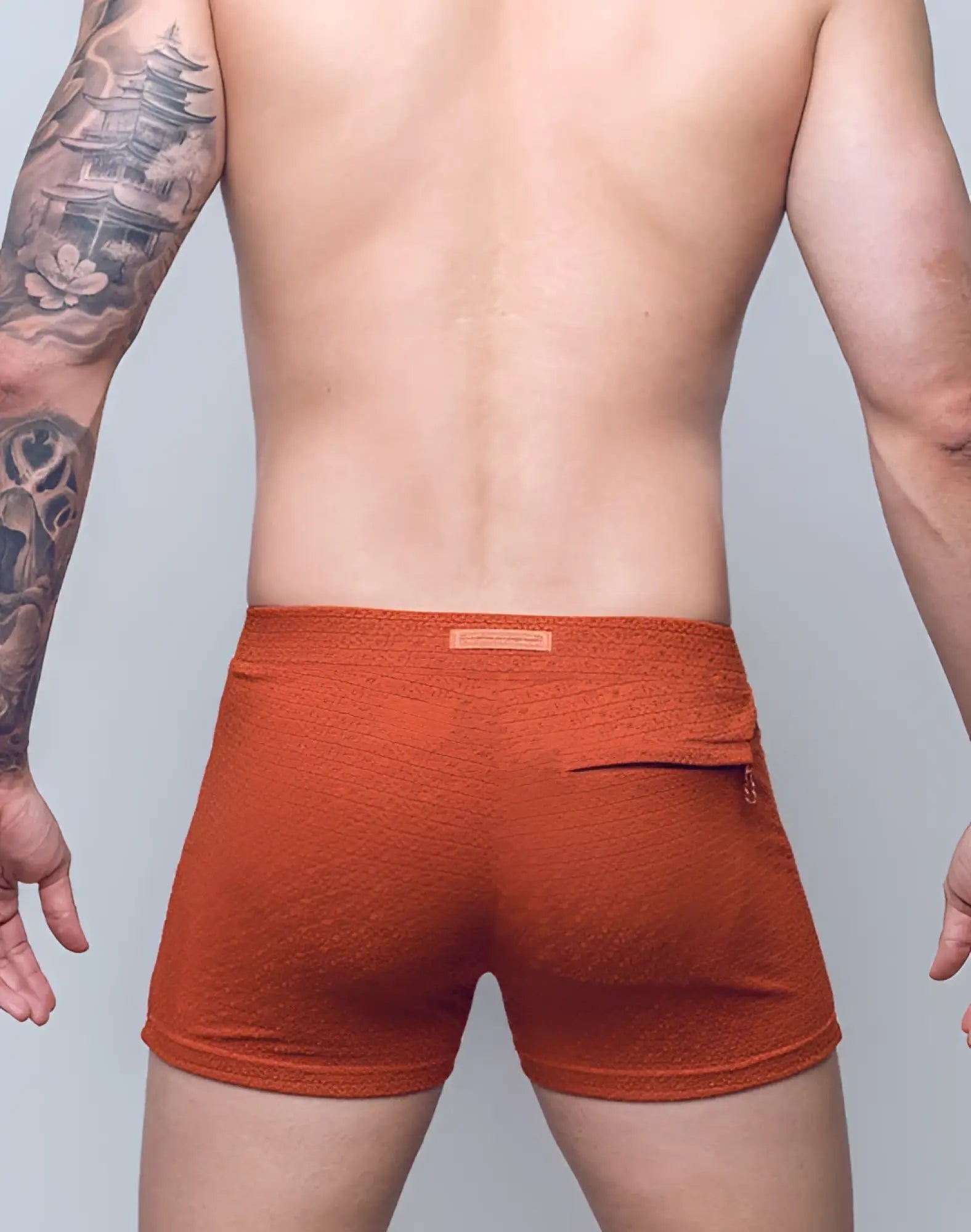 Back side of 2eros v60 textured swim trunk in signet carmine with orange textured fabric and small zippered pocket