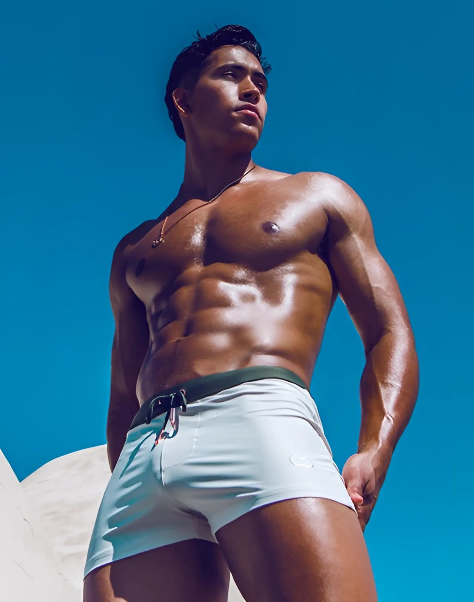 Light blue 2EROS V65 swim trunks with dark green waistband and white logo designed for comfortable swimming