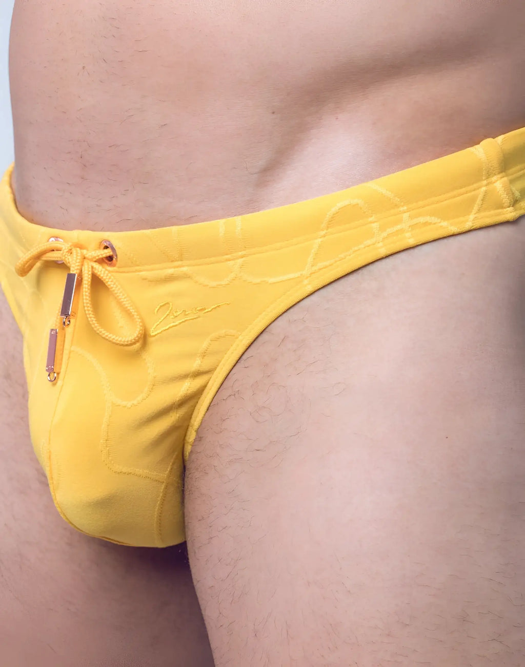 Bright yellow 2EROS V80 textured swim thong with subtle wave pattern and matching drawstring closure