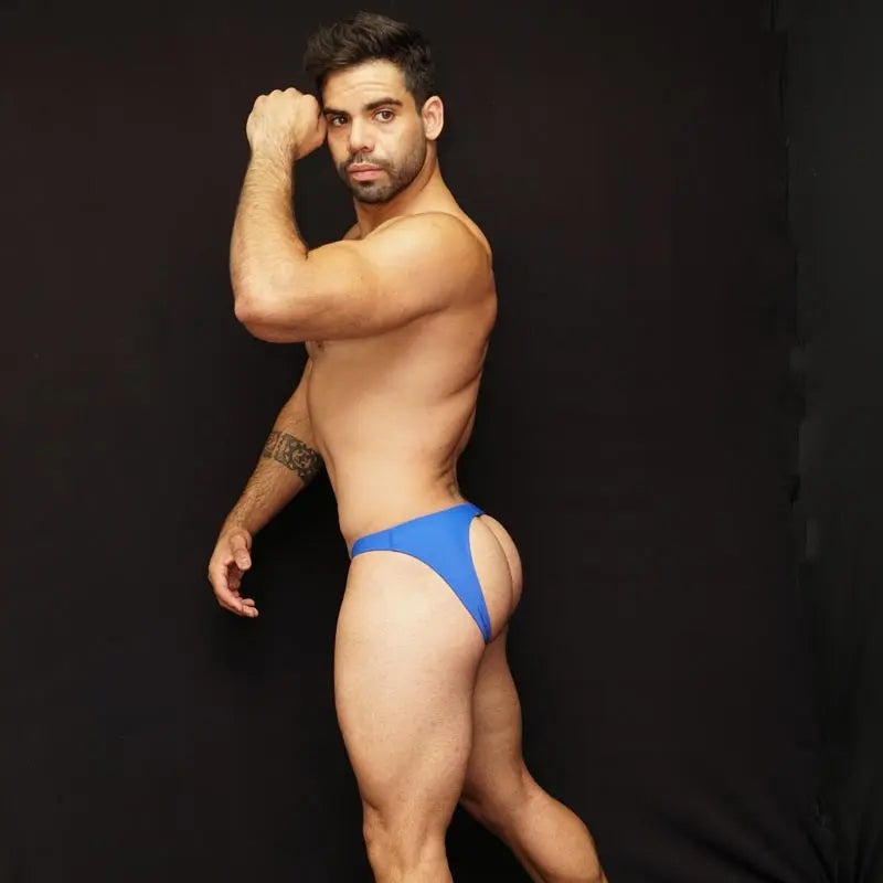 Blue bikini jockstrap underwear by Arroyman featuring a minimal design and a snug fit modeled by a man against a dark background.