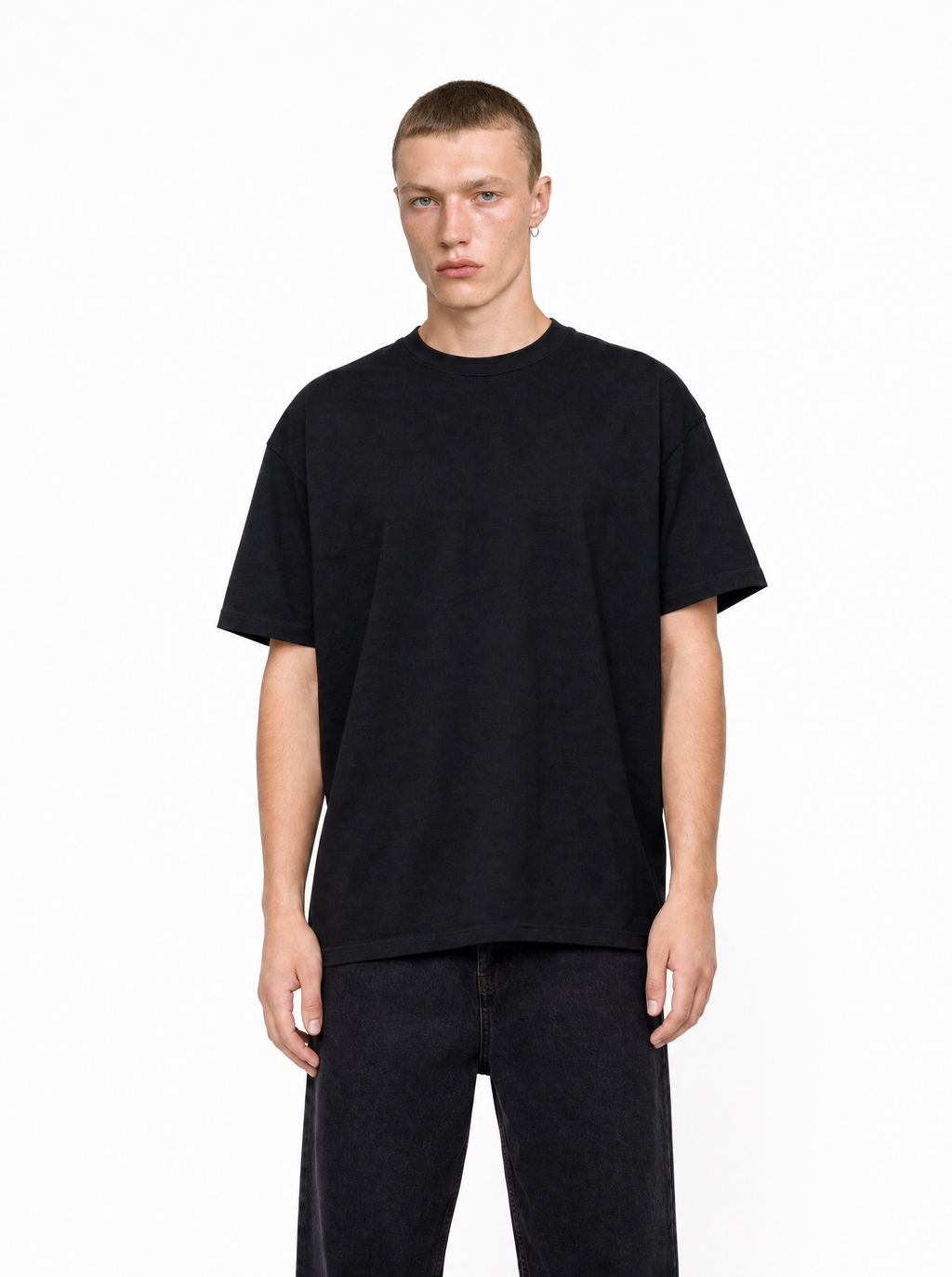 A man wearing a black, loose-fit Core Tee with a crew neck and dropped shoulders, styled with dark jeans.