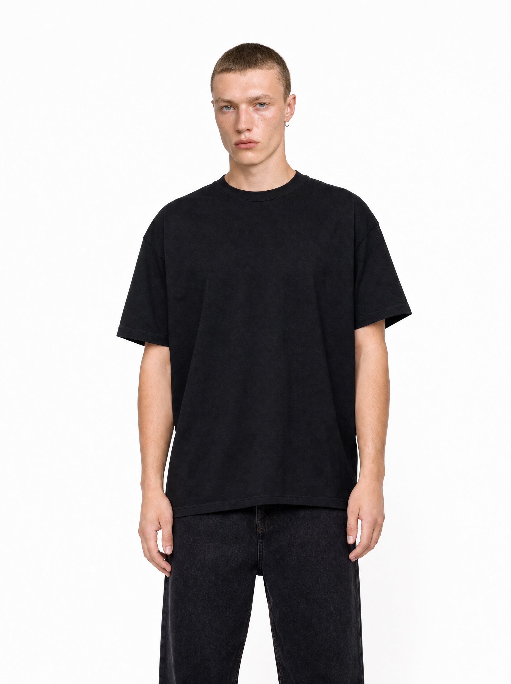 A man wearing a black, loose-fit Core Tee with a crew neck and dropped shoulders, styled with dark jeans.