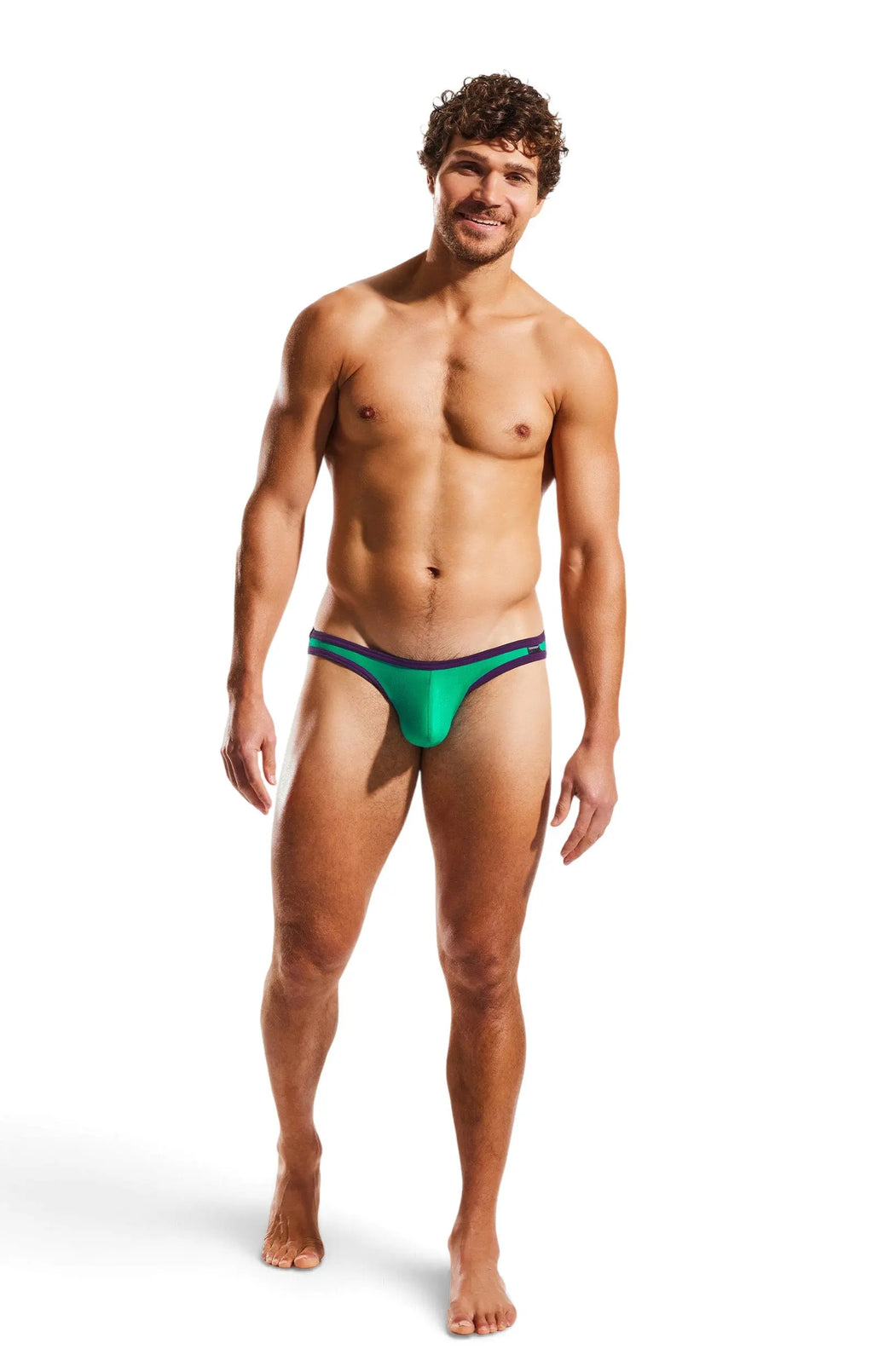 Smiling man standing on a white background wearing green briefs with purple trim.