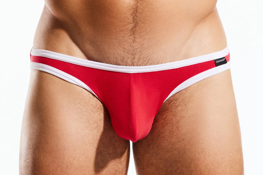 Close-up of a person's midsection wearing red briefs with white trim on a white background.