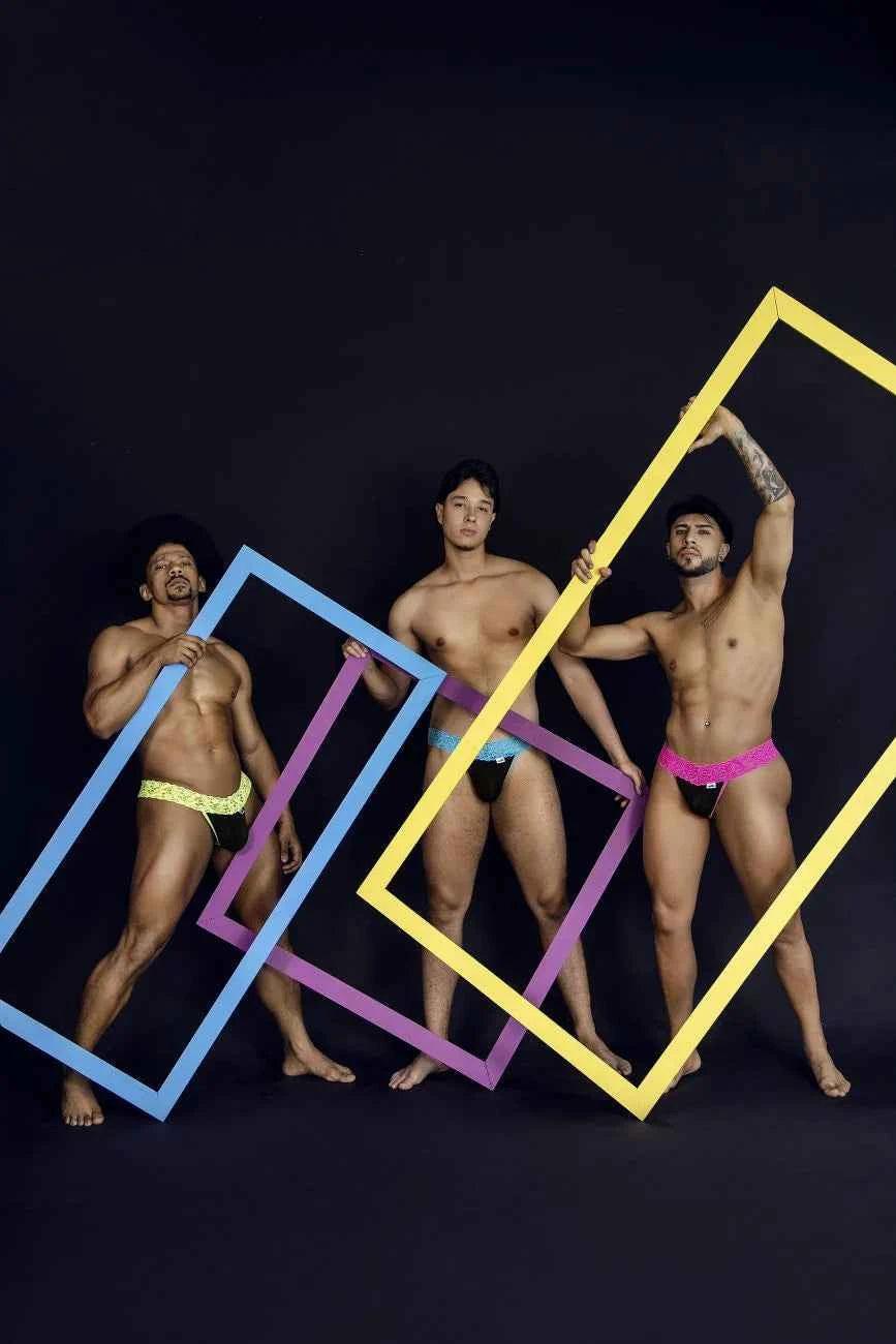 Three men pose with colorful, oversized rectangular picture frames, blue, purple, and yellow, in front of a dark background.
