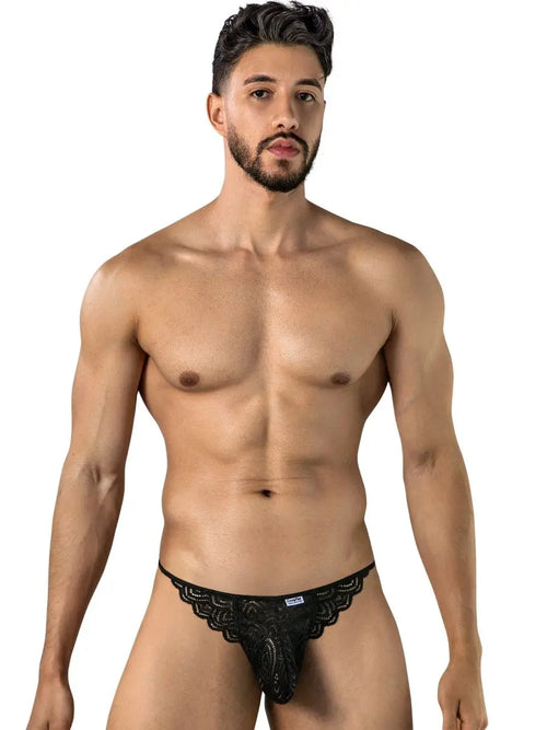 Bearded man standing against a white background wearing black patterned briefs.