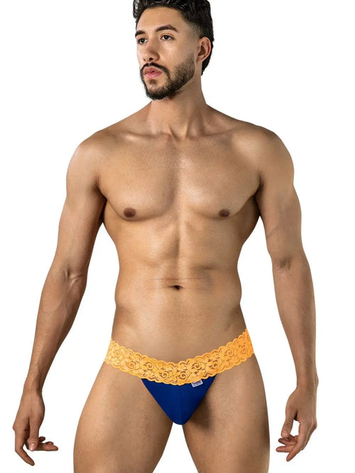 Bearded man standing against a white background wearing blue briefs with an orange patterned waistband.