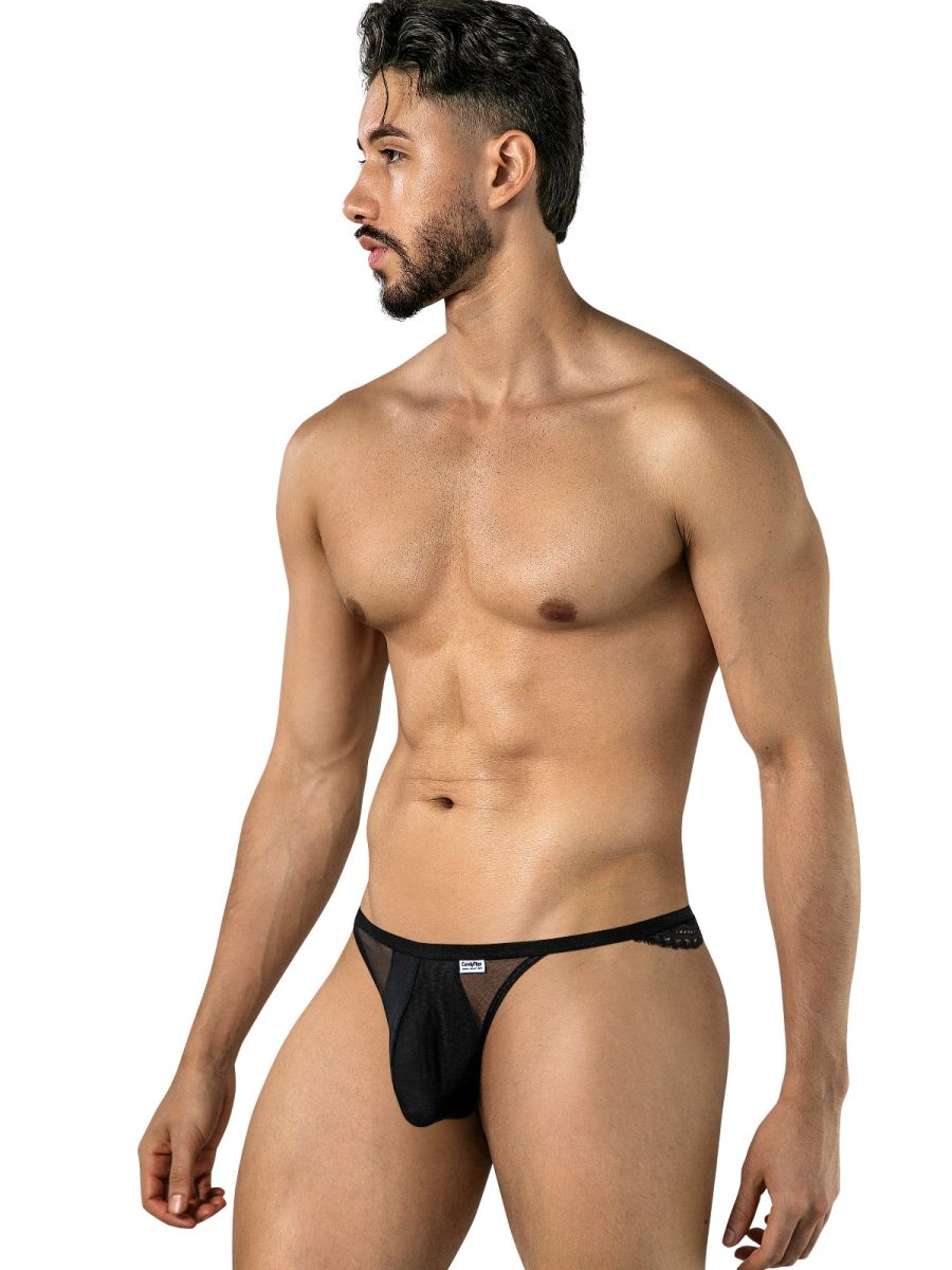 Angled front view of a model wearing a black CandyMan mesh thong with lace at the back.