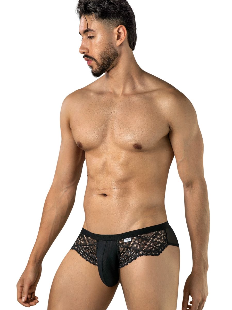 Angled front view of a model wearing black CandyMan briefs with lace panels and a mesh pouch.