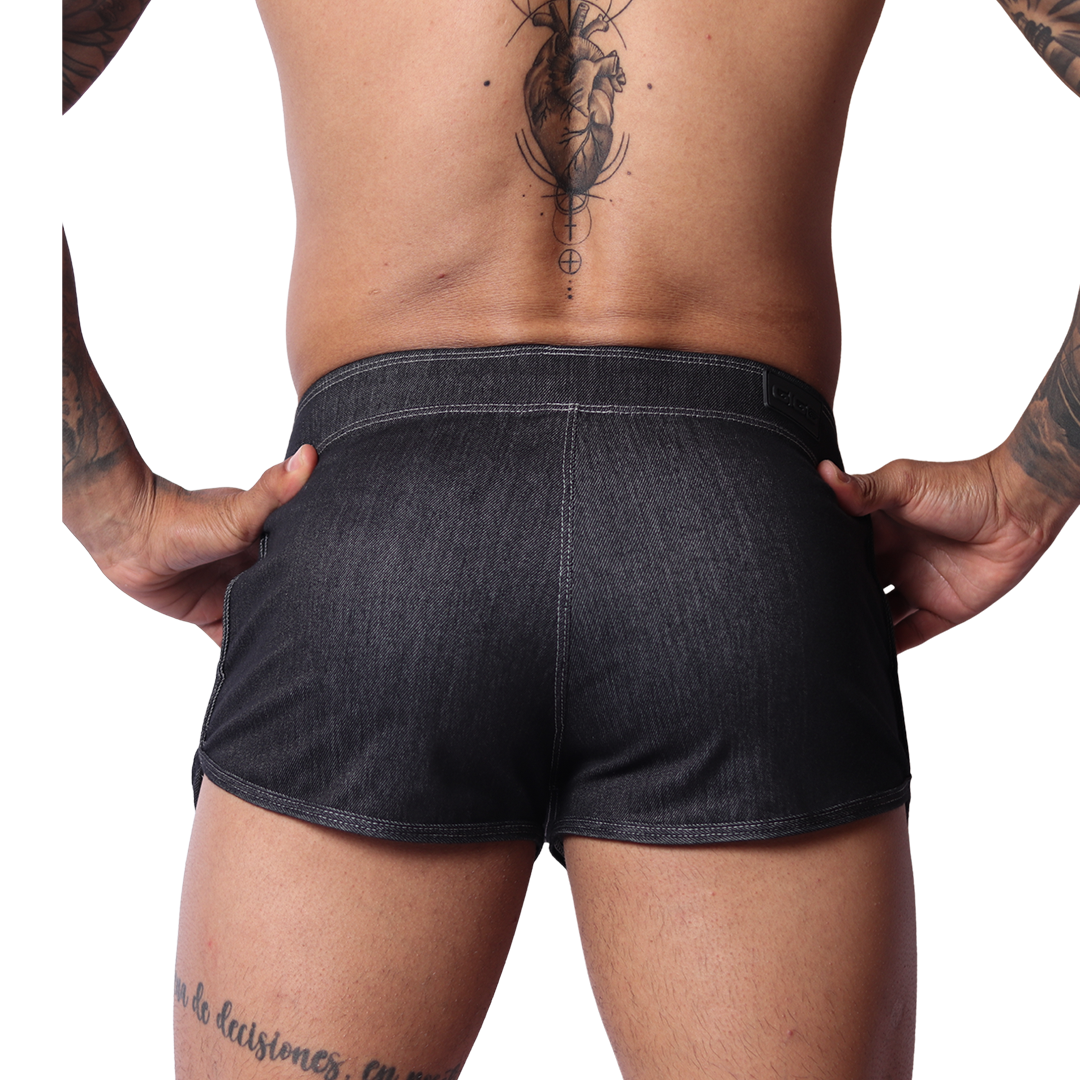Back view of Gigo black denim hot shorts with visible contrast stitching, worn by a man against a black background.