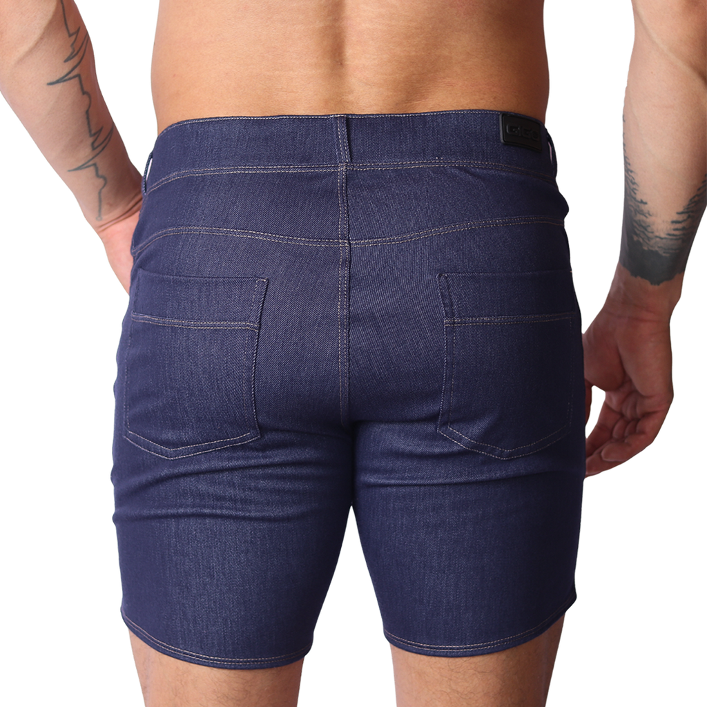 Back view of Gigo blue denim fabric shorts featuring two back pockets and a black logo tag on a black background.
