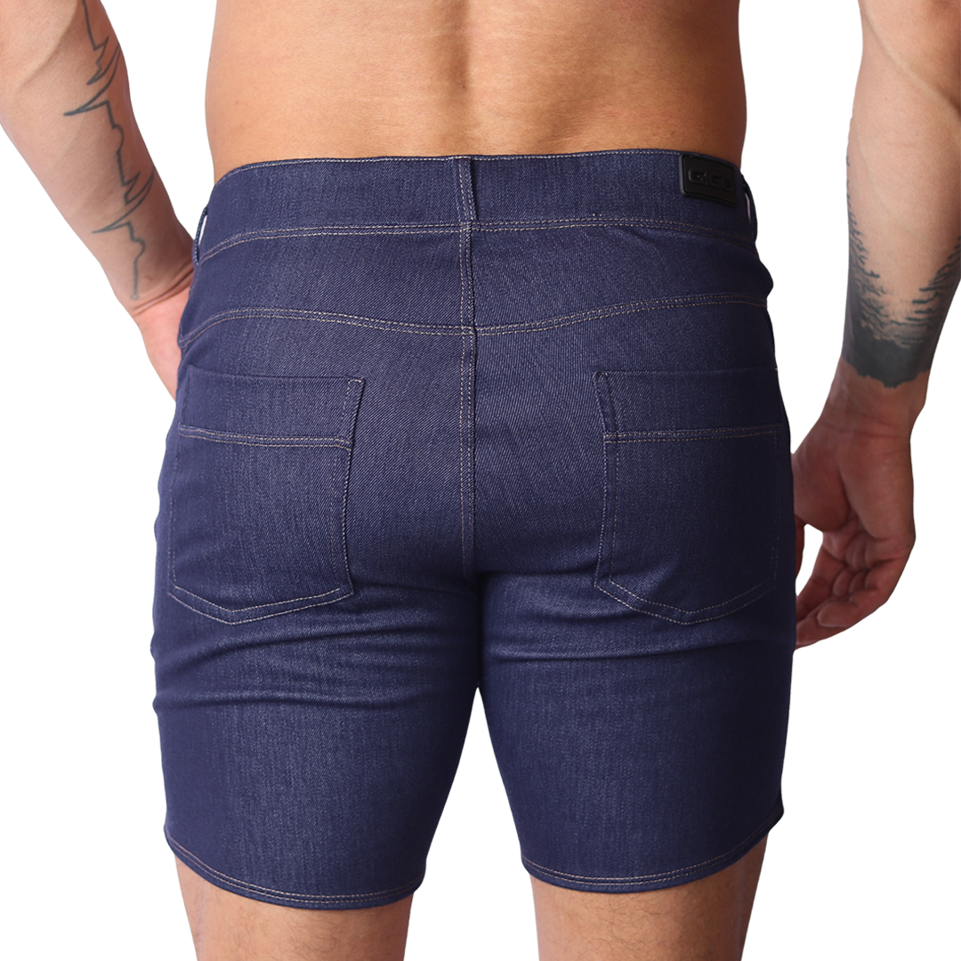 Back view of Gigo blue denim fabric shorts featuring two back pockets and a black logo tag on a black background.