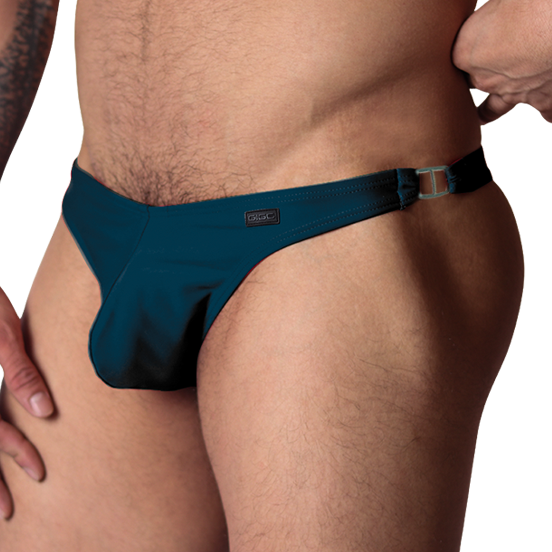 Gigo Dinamic green swim G-string, side view showing stretch fabric, metal side ring, and Gigo branding patch.