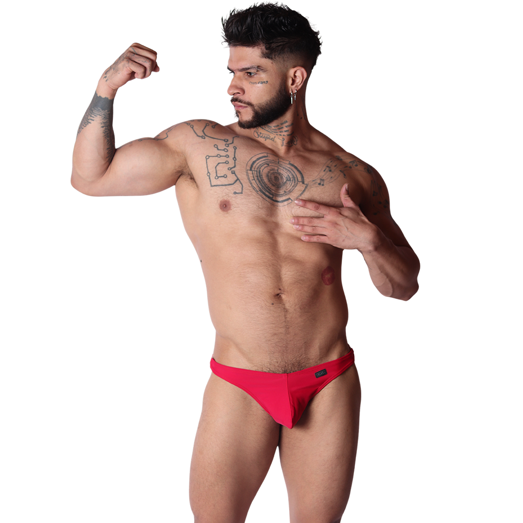 Front view of Gigo Dinamic red swim G-string in smooth fabric with a small logo tag, worn by a muscular tattooed model.