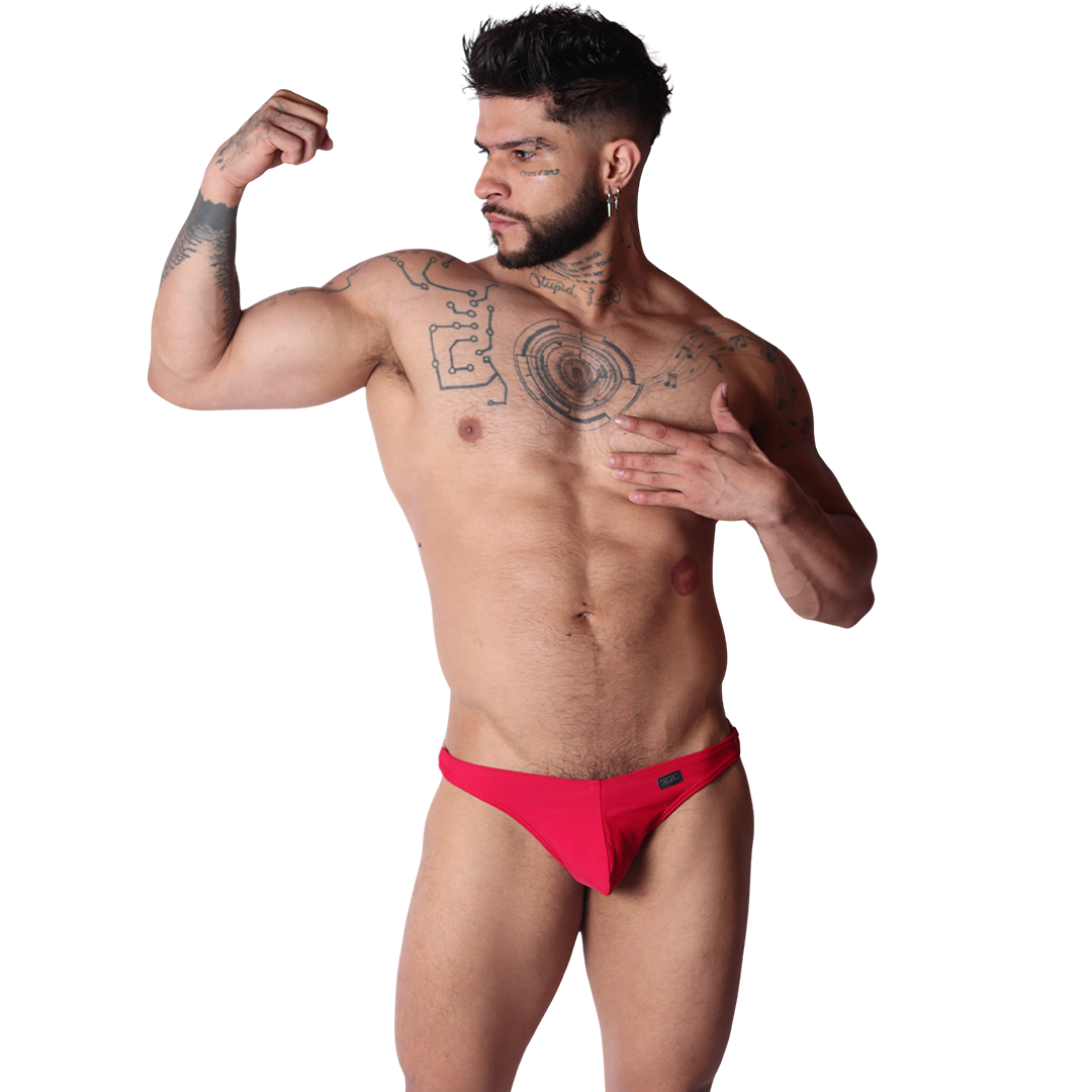 Front view of Gigo Dinamic red swim G-string in smooth fabric with a small logo tag, worn by a muscular tattooed model.