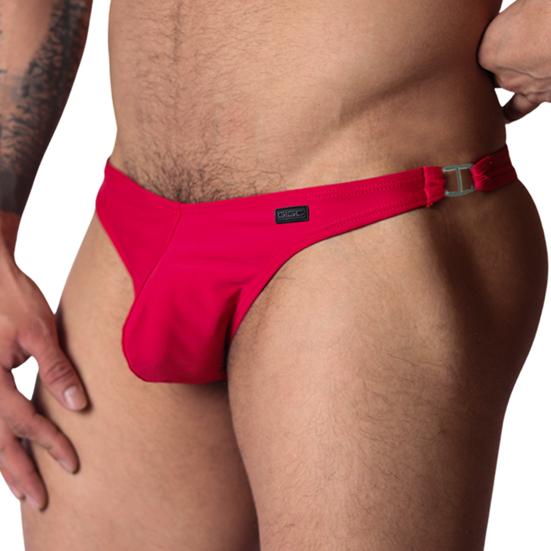 Front view of Gigo Dinamic red swim G-string with metallic side ring detail and logo tag on smooth fabric.