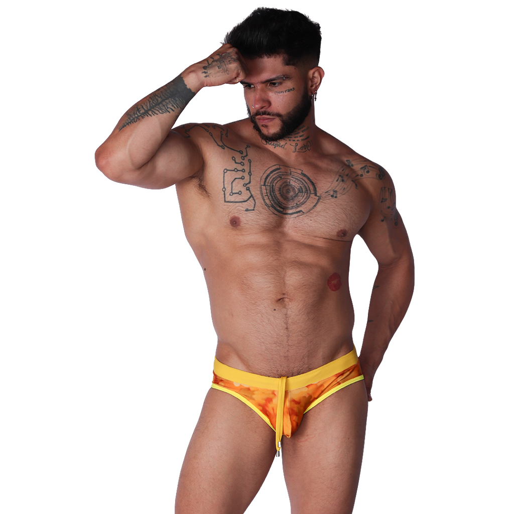 Front view of Gigo yellow floral print swim brief with adjustable drawstring and stretchy fabric on a tattooed male model.