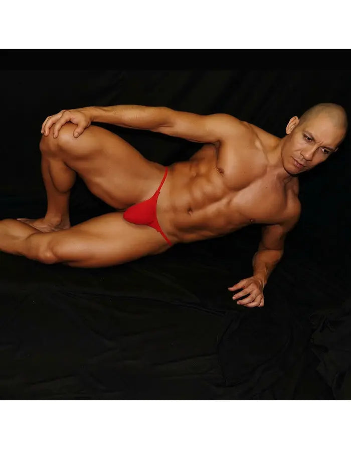 Red thong G-string underwear by Arroyman featuring a minimal design worn by a model against a dark background.