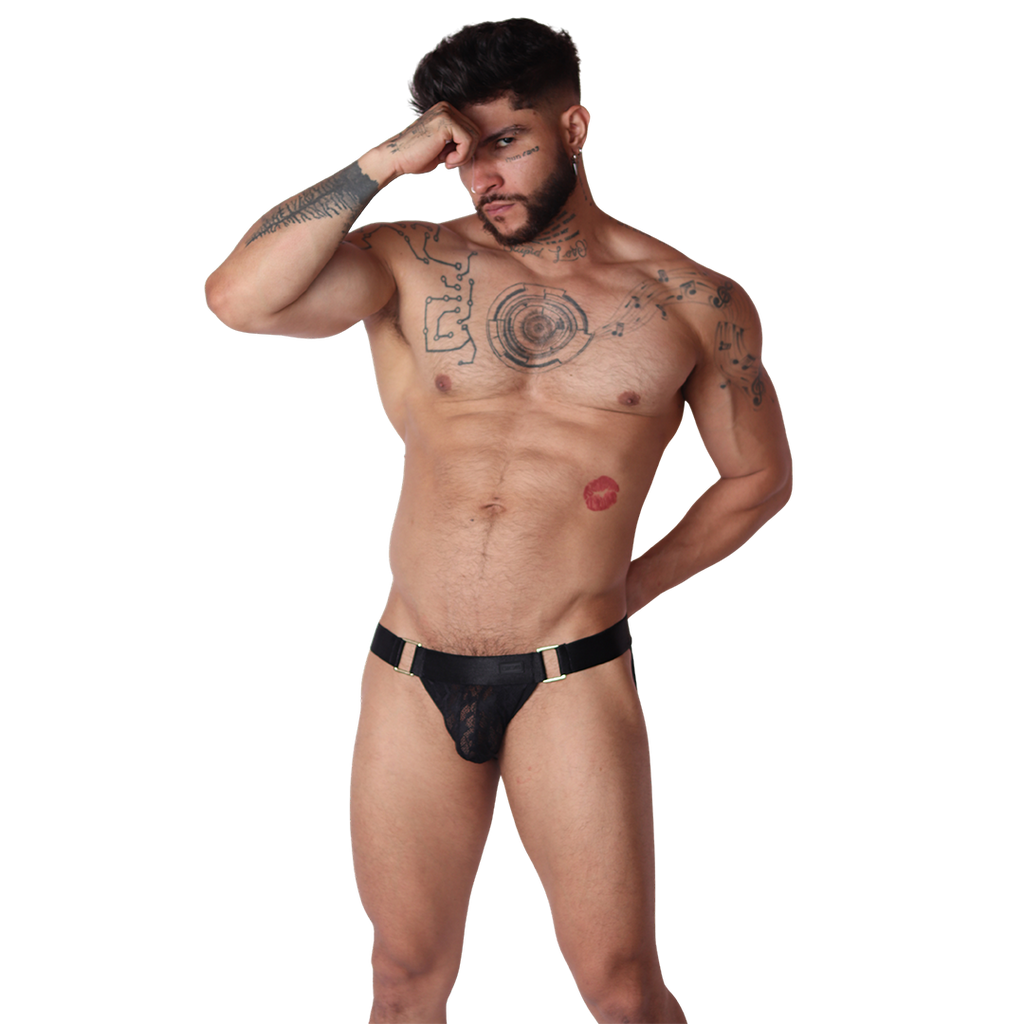 Front view of Gigo Illusion black lace jockstrap with gold ring hardware detailing on a tattooed male model.