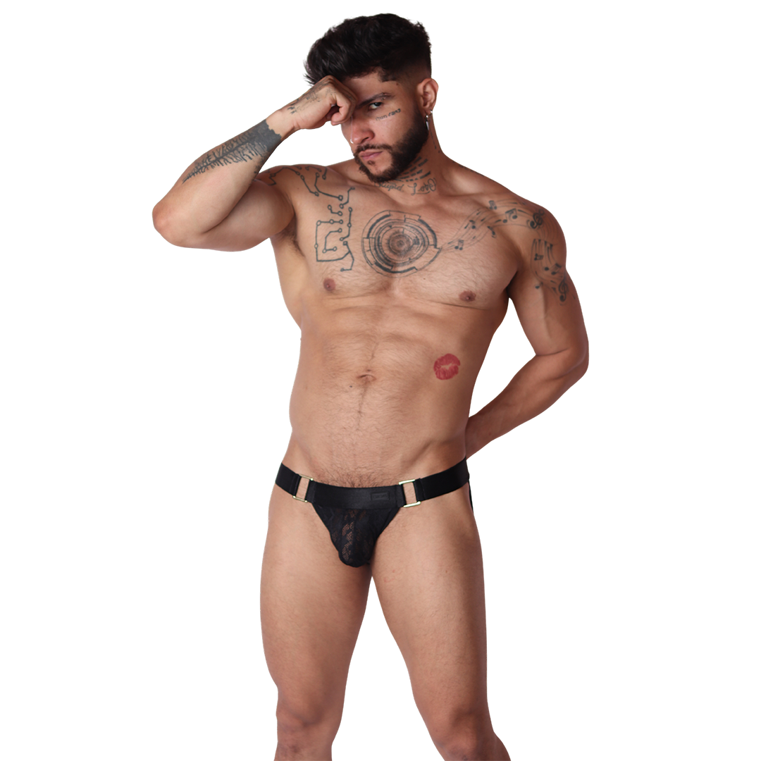 Front view of Gigo Illusion black lace jockstrap with gold ring hardware detailing on a tattooed male model.