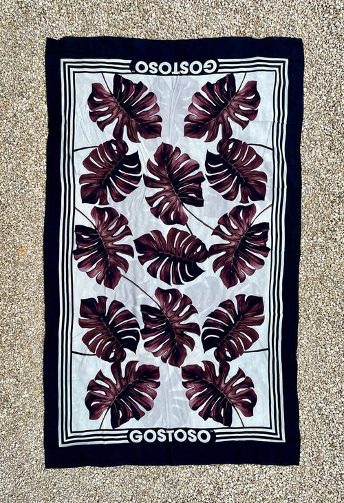 Rectangular textile with dark leaf patterns and a navy border.