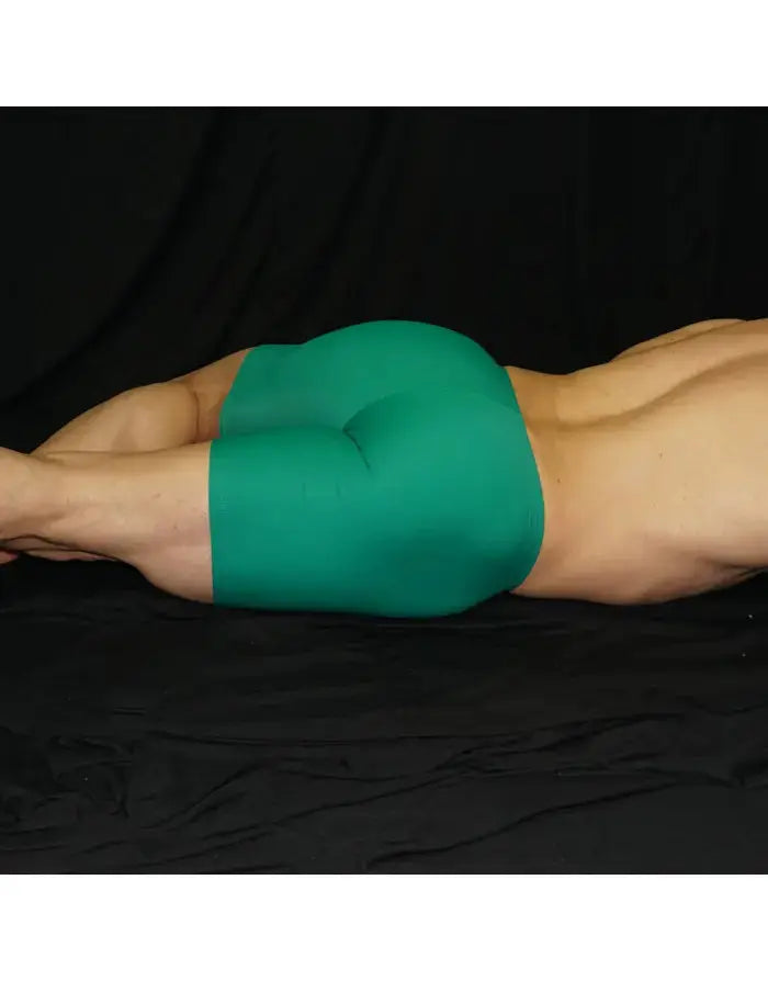 Green compression shorts by Arroyman featuring a snug fit and smooth fabric shown on a model lying down.