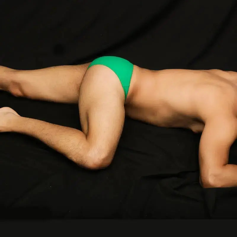 Green bikini swimsuit by Arroyman featuring a snug fit and minimal coverage shown on a model lying down.