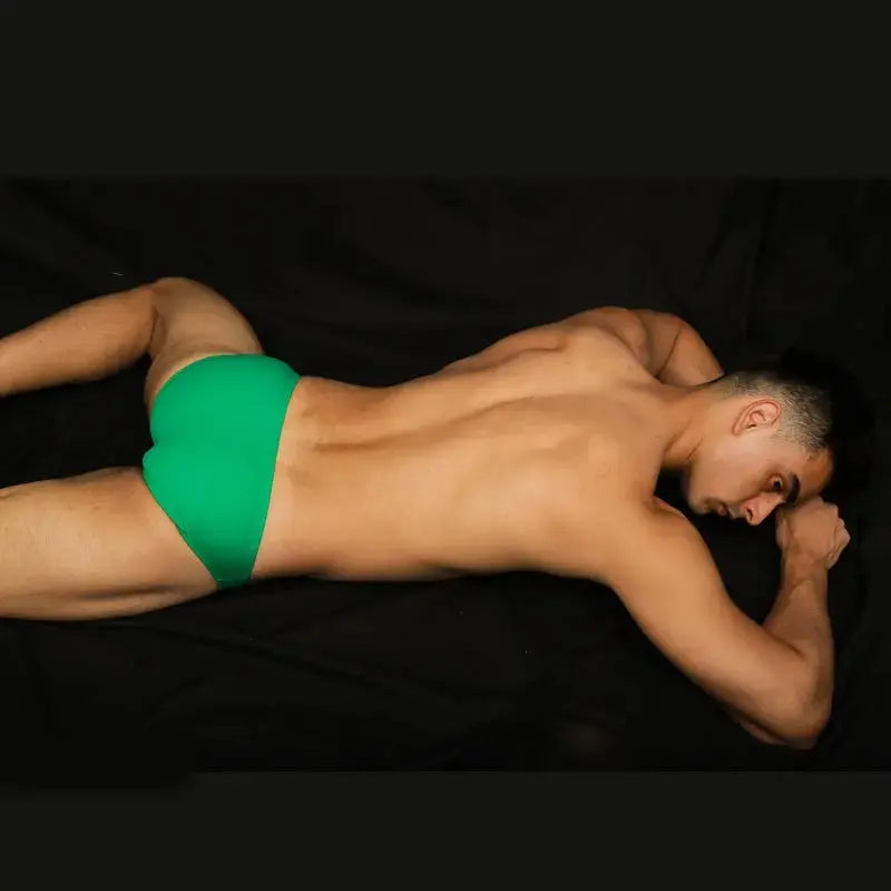 Green bikini swimsuit by Arroyman featuring a snug fit and minimal coverage shown on a model lying down.