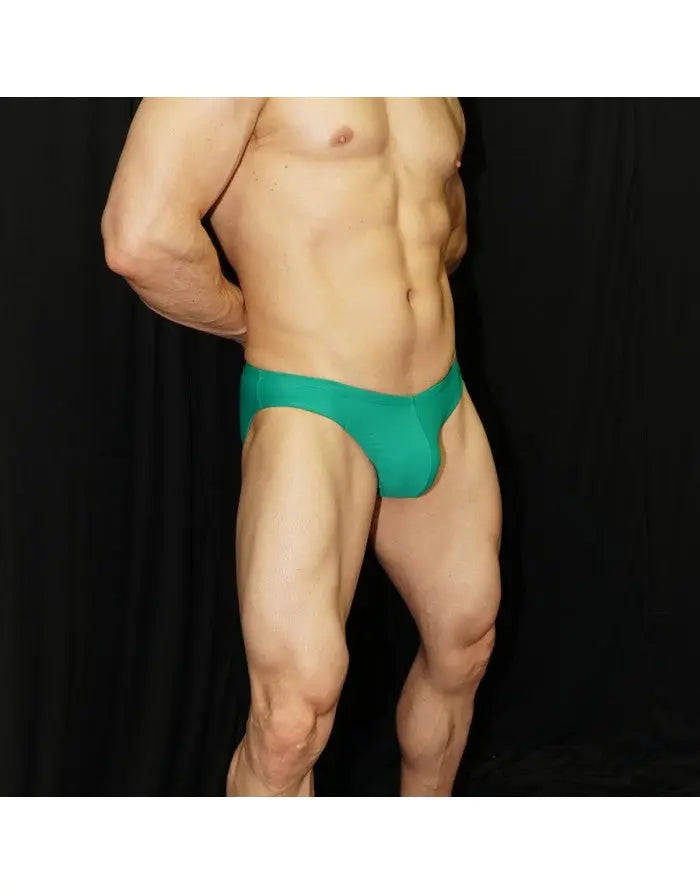 Green bikini swimsuit by Arroyman featuring a snug fit and smooth fabric modeled by a man against a black background.