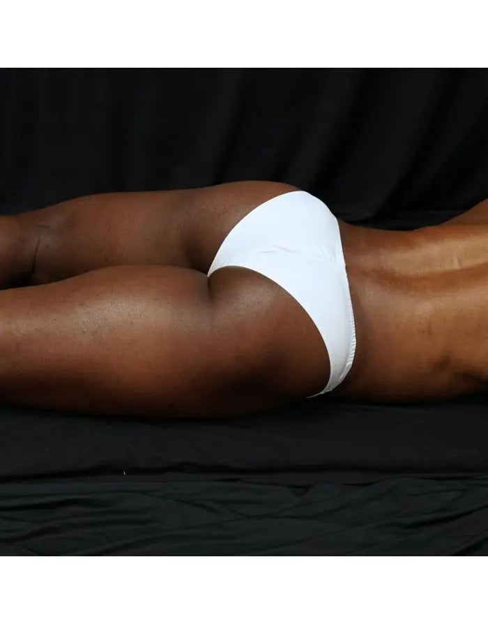 White micro bikini brief by Arroyman featuring a snug fit and minimal coverage shown on a model lying down.