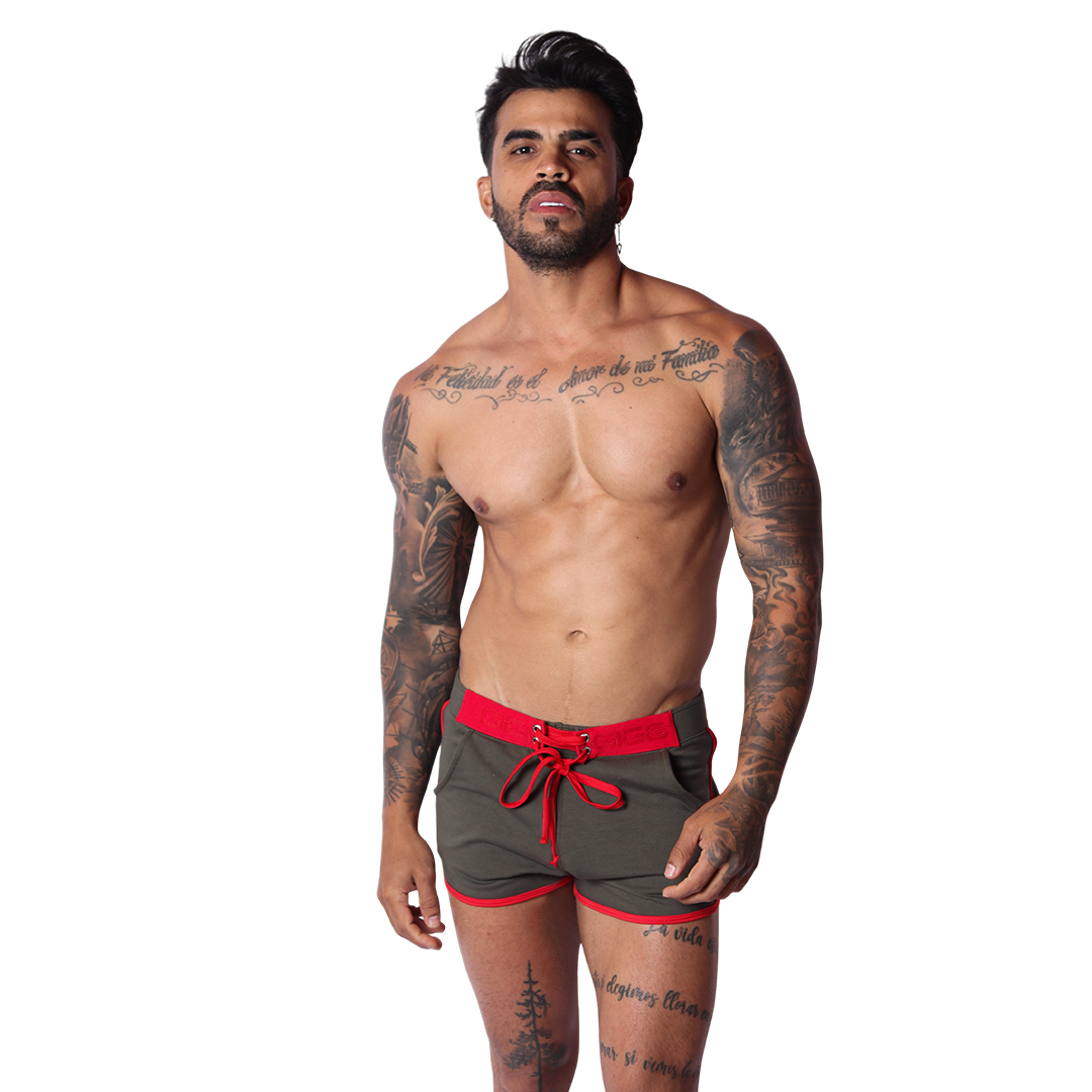 Front view of Gigo Nafts green cotton shorts with red lace-up waistband and trim on a tattooed male model.