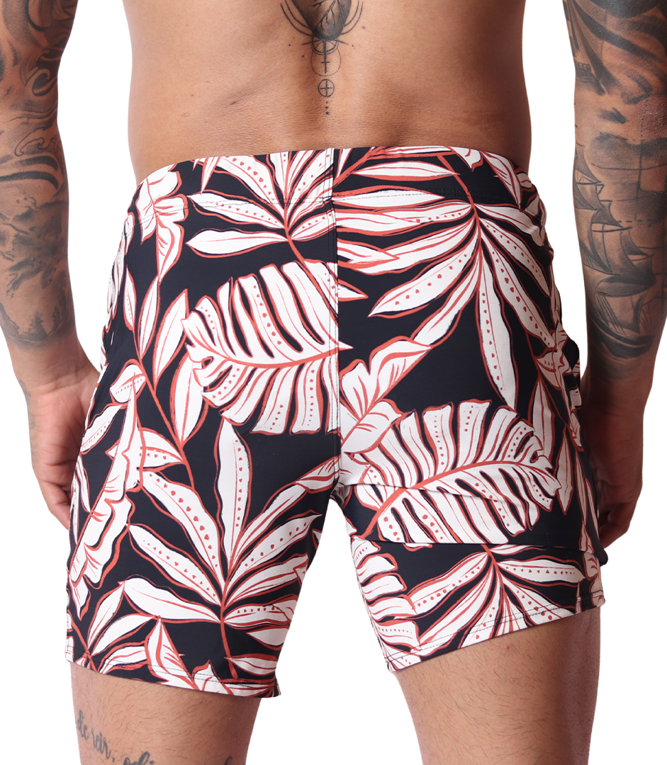 Back view of Gigo Prisma black beachwear shorts with white and red tropical leaf print, stretchy performance fabric.