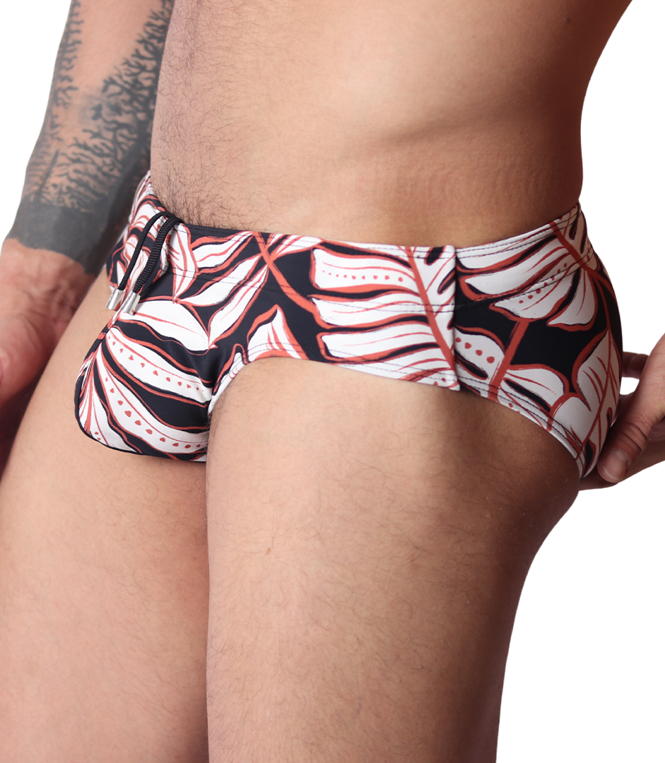 Side view of Gigo Prisma black swim brief featuring a white and red tropical leaf print and drawstring waist detail.