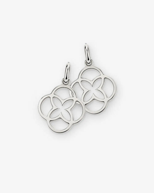 Two silver-tone openwork flower charms with oval jump rings on a white background