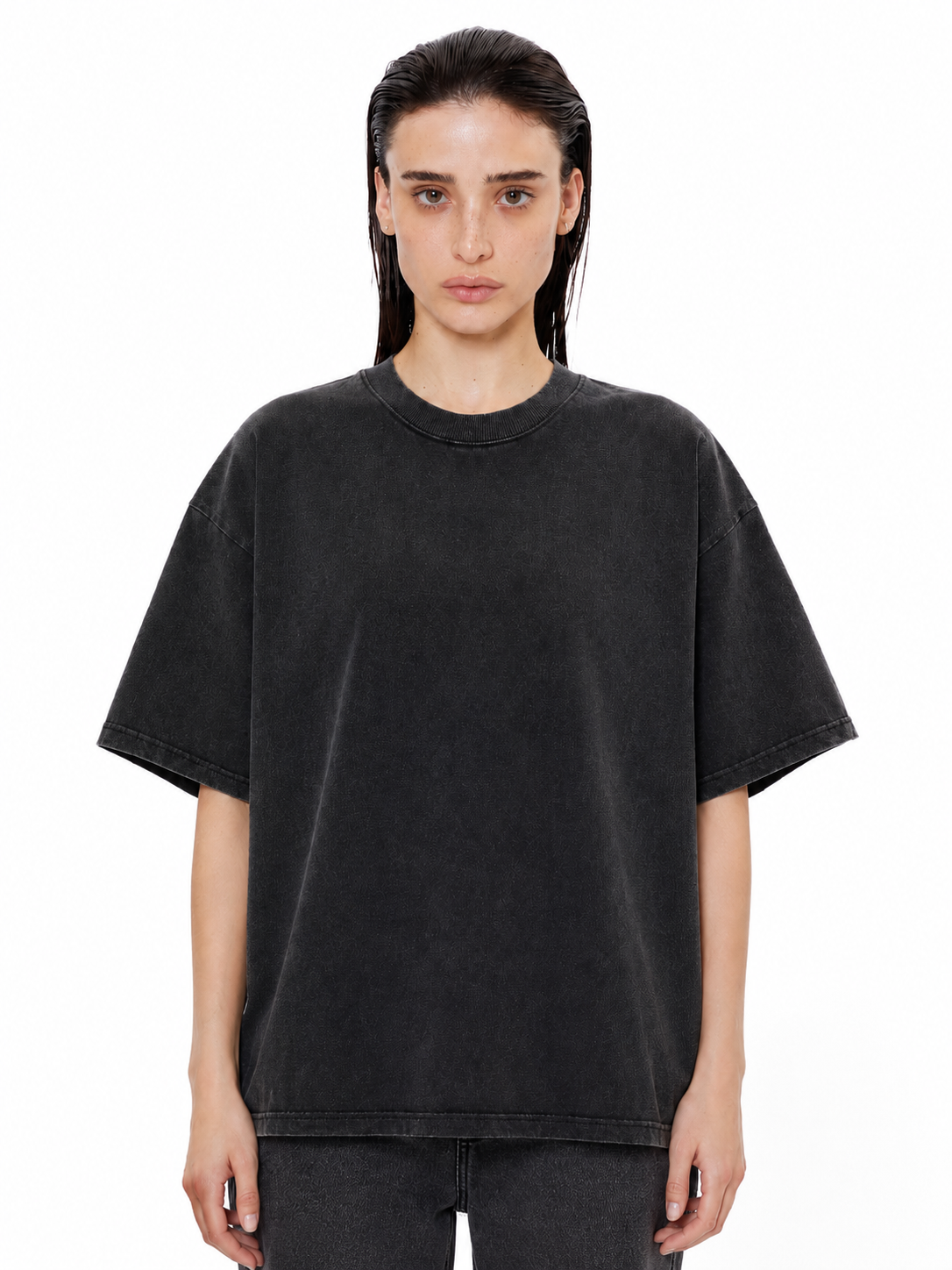 Model wearing an oversized, vintage-wash charcoal black crewneck t-shirt with drop shoulders and a ribbed collar.