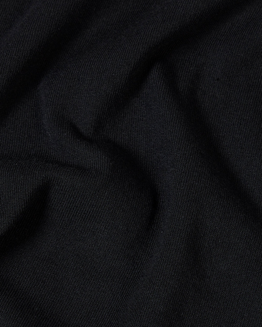 Close-up view of soft, black cotton fabric with subtle folds and a fine-knit texture.