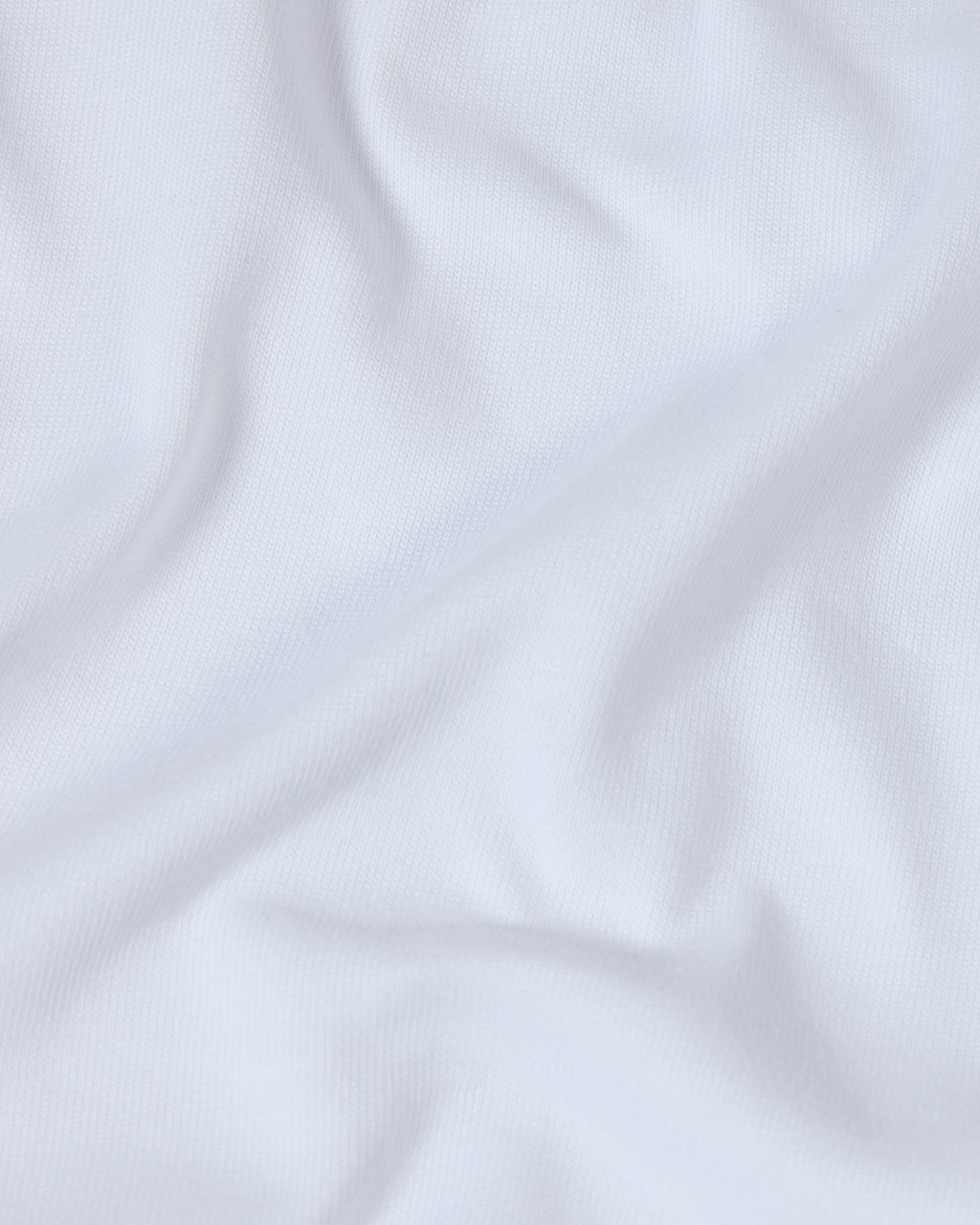 Close-up of a soft, white premium cotton fabric with gentle folds, showing a fine-knit texture.