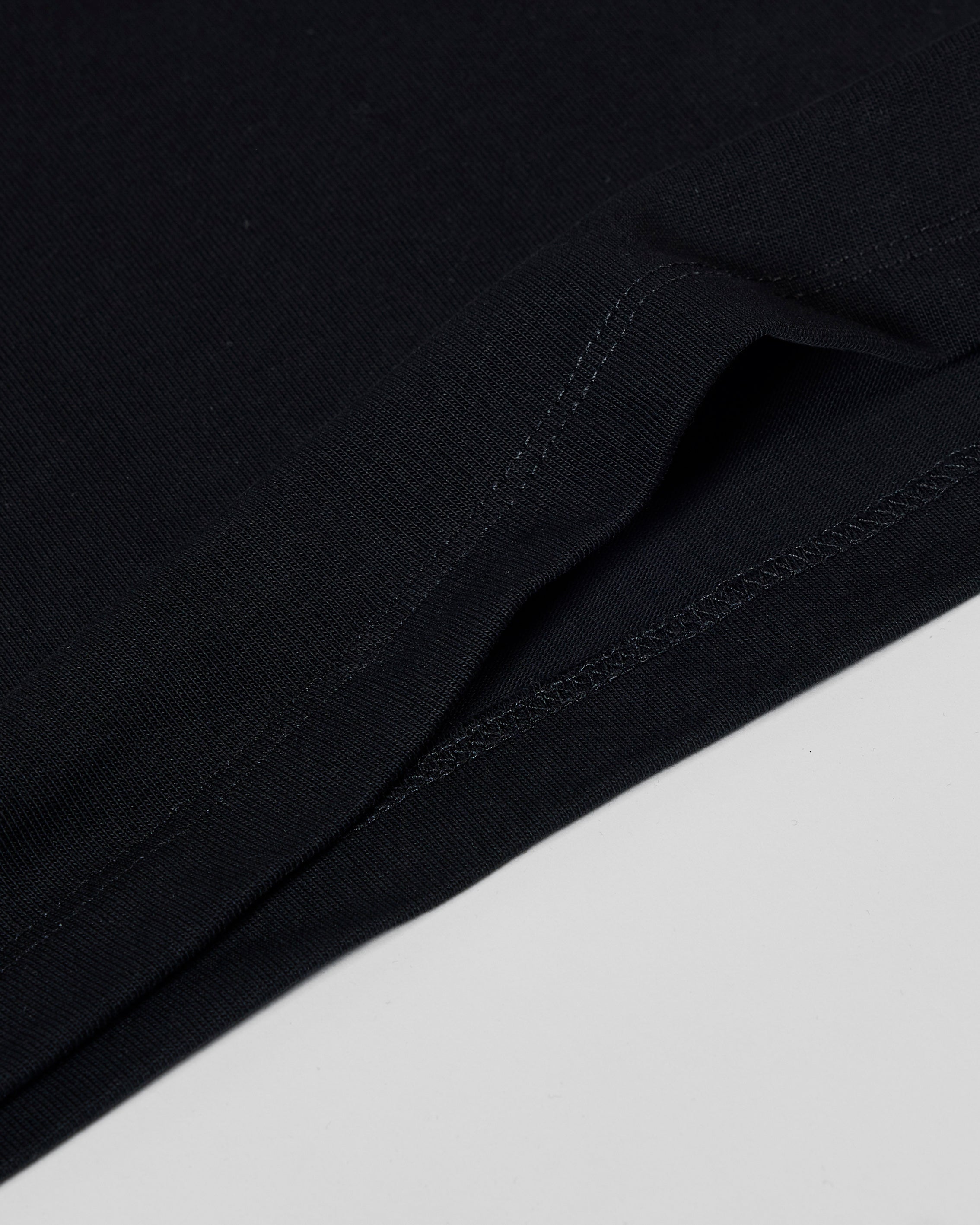 Close-up of a black premium tee showing the high-quality fabric texture and detailed stitched hem.